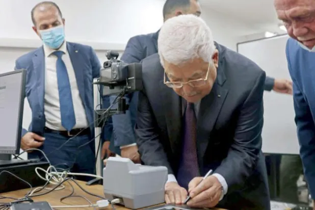 فلسطینی صدر محمود عباس جمعرات کو رام اللہ میں وزارت داخلہ میں اپنے بائیو میٹرک پاسپورٹ کی رجسٹریشن کے دوران ڈیجیٹل طور پر دستخط کر رہے ہیں (اے ایف پی)