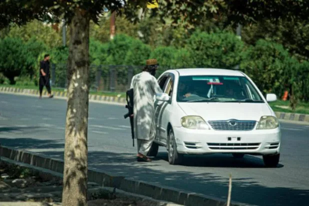گزشتہ روز کابل میں خودکش حملے کا نشانہ بننے کے بعد ایک طالبان جنگجو کو روسی سفارت خانے کے قریب کار ڈرائیور سے بات کرتے ہوئے دیکھا جا سکتا ہے (اے ایف پی)