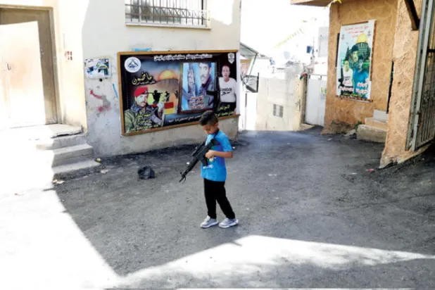 طفل فلسطيني يلهو بمسدس - لعبة خلال جنازة حمد مصطفى أبو جلدة في مخيم جنين بالضفة (إ.ب.أ)