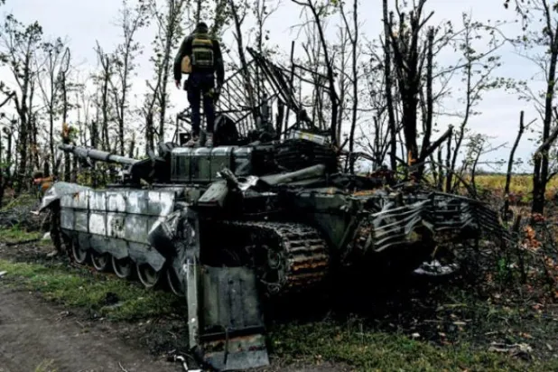 خارکیو کے مضافات میں روسیوں کی طرف سے ترک کیے گئے ایک خراب ٹینک پر یوکرین کے ایک فوجی کو کھڑا دیکھا جا سکتا ہے (اے ایف پی)