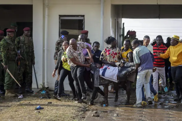 أشخاص يحملون رجلاً مصاباً في استاد كاساراني (أ.ب)