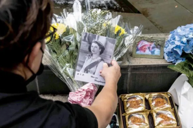 ہانگ کانگ میں برطانوی قونصل خانے کے باہر ایک شخص کو ملکہ الیزابتھ کے لئے گلاب کے پھول بچھاتے ہوئے دیکھا جا سکتا ہے (اے ایف پی)