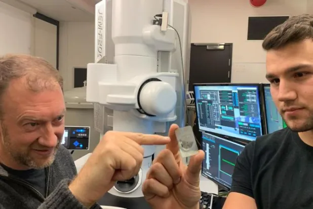 الجيولوجي آندي تومكينز (يسار) وألان سالك المؤلف المشارك في الدراسة ينظران إلى عينة من نيزك (سي إن إن)