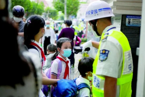 یکم ستمبر کو شنگھائی کے ایک اسکول میں داخل ہوتے ہوئے گارڈ طلباء کے درجہ حرارت کی پیمائش کر رہا ہے (رائٹرز)