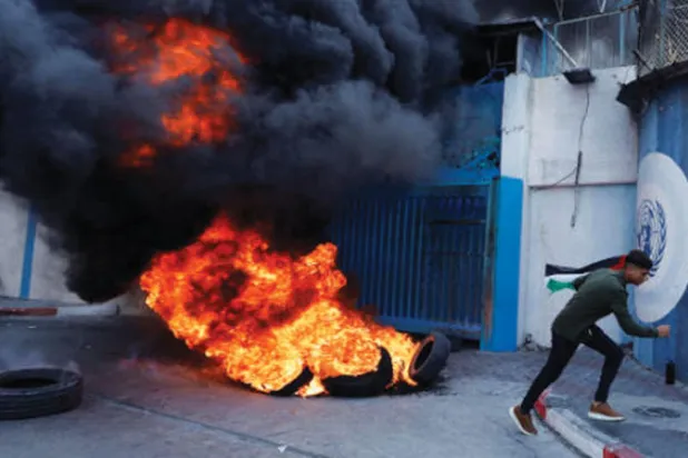 إطارات تحترق خارج مقر «أونروا» في غزة أمس (رويترز)