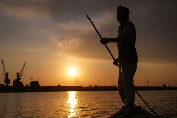Iraqi fisherman Naim Haddad, 40, stands barefoot on his boat at sunset on Shatt al-Arab, the confluence of the Tigris and Euphrates rivers that empties into the Gulf, near the city of Basrah in southern Iraq, on February 12, 2022. (Photo by Ayman HENNA / AFP)