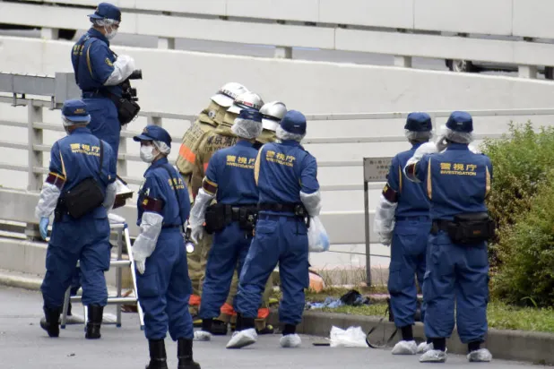 عناصر من الشرطة اليابانية يتفقدون المكان الذي أقدم فيه رجل على حرق نفسه بالقرب من مكتب رئيس الوزراء (رويترز)