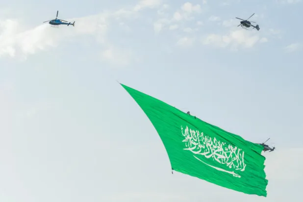 العلم السعودي يرفرف في السماء محمولا بمروحيات خلال احتفال سابق باليوم الوطني (تصوير: علي خمج)