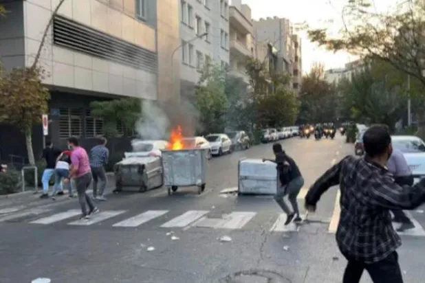 متظاهرون يرشقون شرطة مكافحة الشغب بالحجارة وسط طهران الأسبوع الماضي (أ.ب)