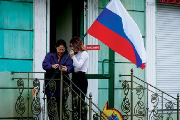 Luhansk'ta referandum sonuçlarının açıklanması ardından evinin önüne Rus bayrağı diken bir kadın (AP)