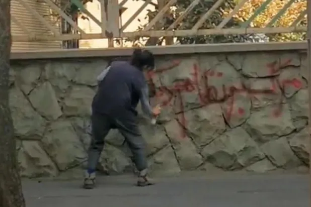 تہران کی ایک دیوار پر ایرانی خاتون "آمرانہ حکومت مردہ باد" کا نعرہ تحریر کر رہی ہے (ٹویٹر)