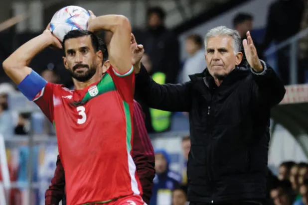 كيروش يتابع المباراة الدولية بين إيران وأوروغواي بينما إحسان حاج صفي ينفذ رمية تماس (رويترز)