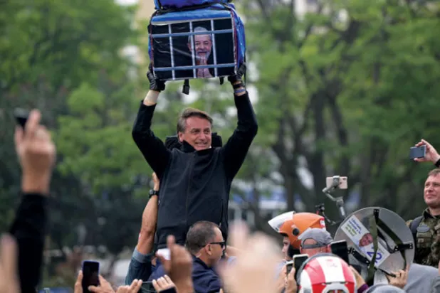 بولسونارو يحمل صورة للولا وراء القضبان في ساو باولو أمس (أ.ف.ب)