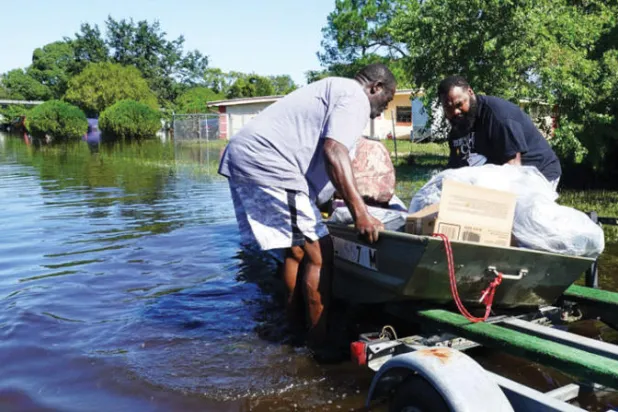 أميركيان ينقلان أمتعتهما بعد إعصار إيان في أورلاندو أمس (أ.ف.ب)