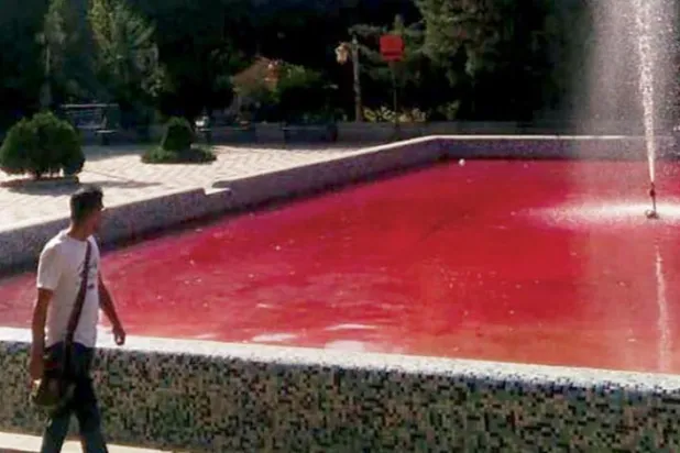 کل تہران کے اسٹوڈنٹ پارک میں "تہران خون سے رنگا ہوا ہے" مہم کے ایک حصے کے طور پر ایک شخص کو سرخ رنگ کے چشمے کے پاس سے گزرتے ہوئے دیکھا جا سکتا ہے (اے ایف پی)