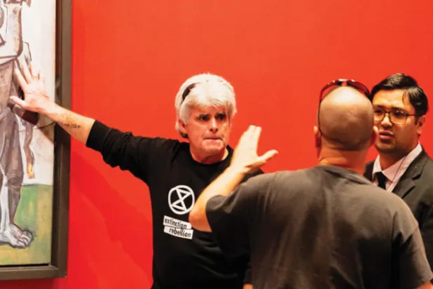 أحد الناشطين يلصق يده بالغراء على الحماية الزجاجية للوحة بيكاسو في متحف بملبورن الاسترالية (أ.ف.ب)