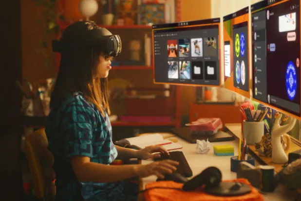 امرأة جالسة على مكتب تعمل على شاشات افتراضية باستخدام خوذة «ميتا كويست برو» (رويترز)