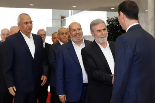 کل دمشق کا دورہ کرنے والے ایک فلسطینی وفد کے ساتھ  الأسد کو النخالہ اور ان کے جانشین خلیل الحیہ سے مصافحہ کرتے ہوئے دیکھا  جا سکتا ہے (سانا - اے پی)