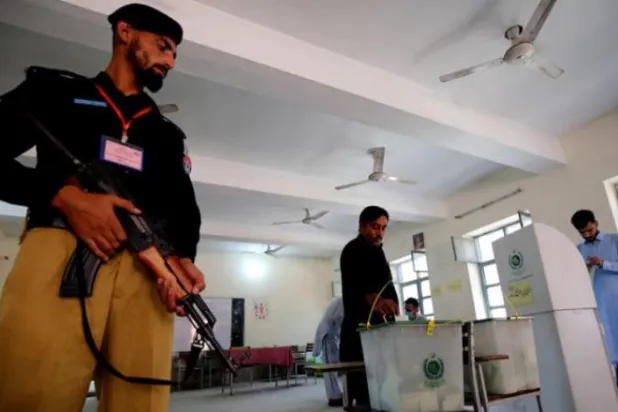 Pakistanlı bir polis memuru, dün Hayber-Pahtunhva eyaletinin Peşaver kentinde yapılan ara seçimde bir vatandaş oy kullanırken merkezde nöbette (AFP)