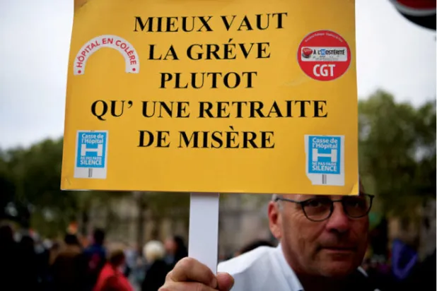 فرنسي يحمل لافتة كتب عليها «إن الإضراب أفضل من التقاعد البائس» خلال مظاهرة في باريس قبل أيام (أ.ف.ب)