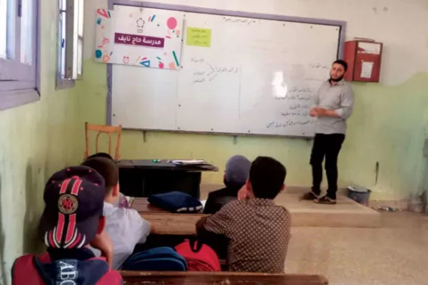 معلم يقدم الدروس لعدد من الطلاب في مدرسة بمدينة إدلب (الشرق الأوسط)