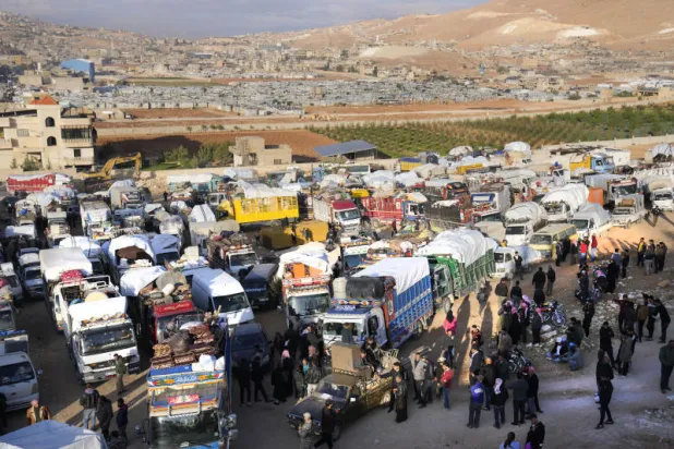 لاجئون سوريون يتجمعون بالقرب من الشاحنات في بلدة عرسال شرقي لبنان استعدادا للعودة إلى سوريا  (أ.ب)