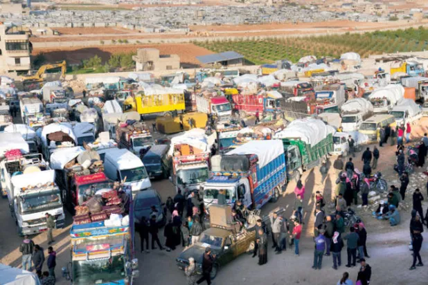 عائلات سورية تتجمع قرب شاحنات في بلدة عرسال في منطقة البقاع تمهيداً للعودة (أ.ب)