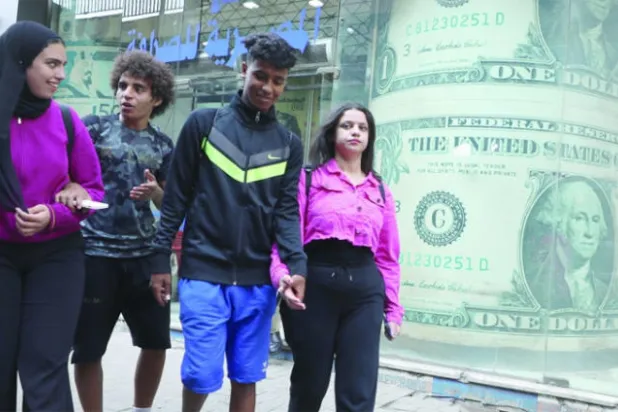 مصريون يمرون أمام أحد محال الصيرفة وسط القاهرة أمس (إ.ب.أ)