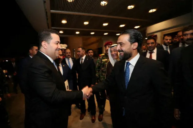 رئيس البرلمان العراقي محمد الحلبوسي - يمين - يصافح رئيس محمد شياع السوداني (رويترز)