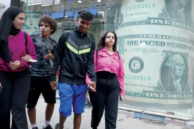 مصريون يمرون أمام أحد محال الصيرفة وسط القاهرة أمس (إ.ب.أ)