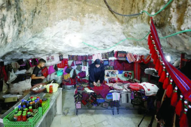 فاطمة النواجعة تعرض ملابس فلسطينية تقليدية في كهف (رويترز)