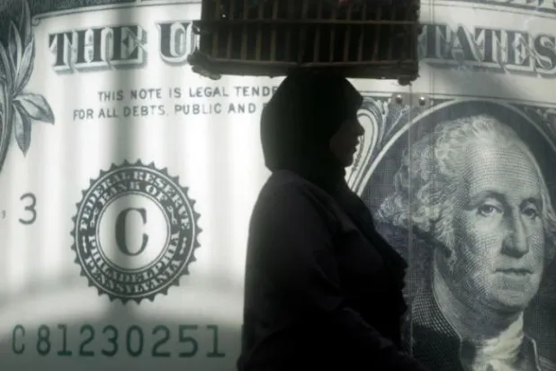 Mısırlı bir kadın, başkent Kahire’deki bir borsa merkezinin önünden geçiyor (AP)