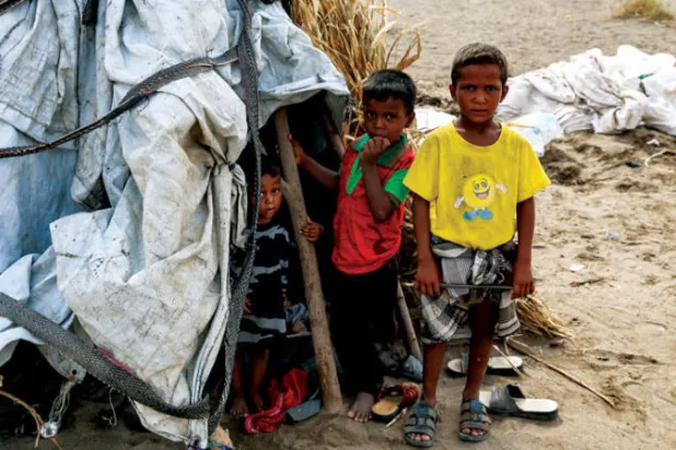 أطفال يمنيون أمام خيمة في مخيم للنازحين بمنطقة الجراحي التابعة لمحافظة الحديدة (أ.ف.ب)