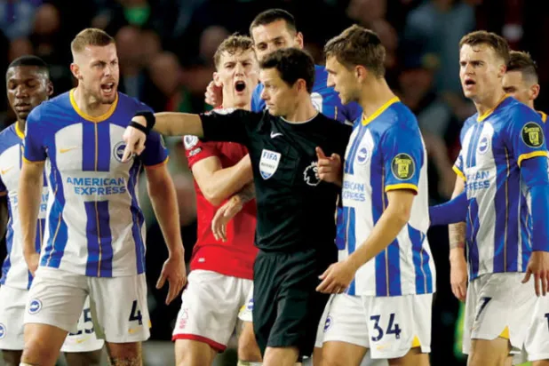 لاعبو برايتون الغاضبون يحيطون بالحكم دارين إنغلاند (رويترز)