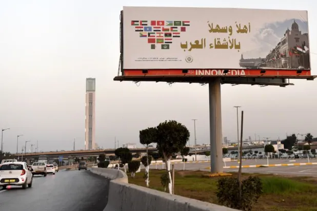لوحة إعلانية ترحب بالقادة العرب في قمة الجزائر (أ.ف.ب)