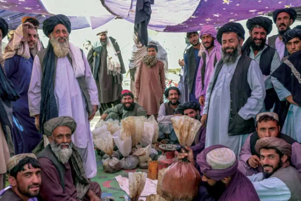 مواطنون أفغان يتجمعون حول أكياس تحتوي على الهيروين والحشيش وهم يتفاوضون ويفحصون الجودة في سوق للمخدرات في ضواحي قندهار سبتمبر 2021 (أ.ف.ب)