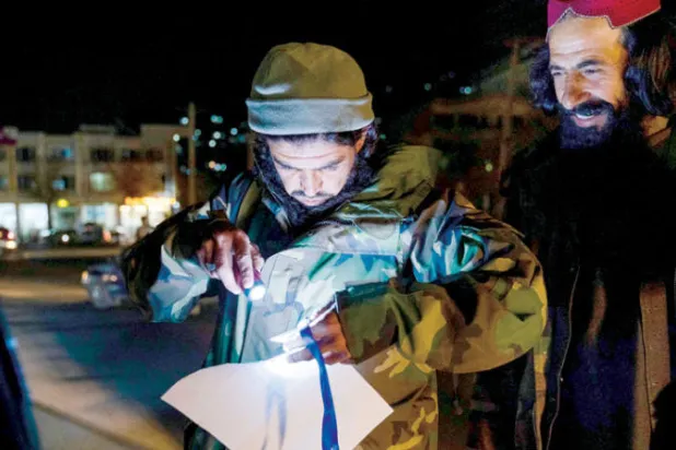 صورة التقطت 23 أكتوبر 2022 لأحد مقاتلي «طالبان» يتفقد أوراقاً ثبوتية عند نقطة تفتيش في العاصمة كابل (أ.ف.ب)