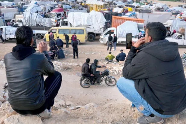 لاجئان سوريان قررا البقاء في لبنان يصوّران قافلة من السوريين العائدين إلى بلادهم في منطقة عرسال الحدودية يوم 26 أكتوبر الماضي (أ.ب)