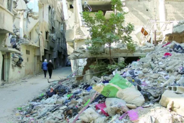Women walk near rubble inside the Yarmouk Palestinian refugee camp on the southern outskirts of Damascus, Syria November 2, 2022. REUTERS/Firas Makdesi