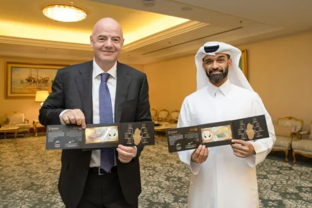 حسن الذوادي وإنفانتينو رئيس الفيفا يحملان تذكاراً من العملات خاصة بكأس العالم (قنا)