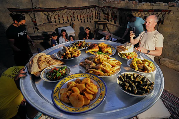Tourists are seen next to a meal made by Saqqara residents, who
sell food to improve their living conditions in thier village, in
Giza, Egypt, on April 27, 2021. REUTERS/Shokry Hussien
