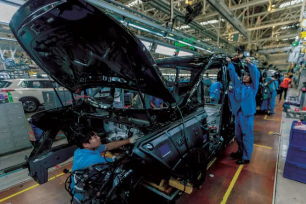 موظفون على خط تجميع في مصنع للسيارات في نانجينغ الصينية بمقاطعة جيانغسو (إ.ب.أ)