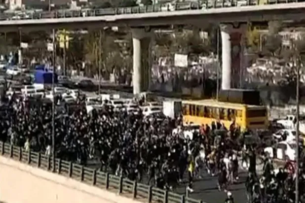 متظاهرون يسيرون على طول طريق سريع في مدينة كرج شمال إيران مطلع الشهر الحالي (أ.ف.ب)