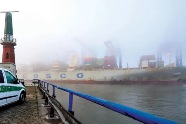 سيارة تابعة للجمارك تتابع مرور سفينة في ميناء هامبورغ الألماني (د.ب.أ)