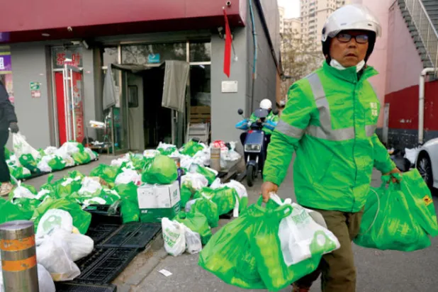عامل توصيل في بكين ينقل بضائع للزبائن طلبوها على الإنترنت (رويترز)