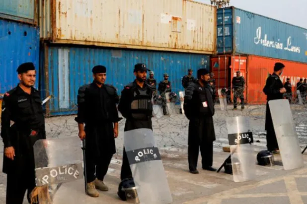 Eski Başbakan İmran Han'ın hükümetin erken seçim kararı alması için baskı yapmak üzere planladığı özgürlük yürüyüşü öncesinde, kırmızı bölgeye girişi engellemek için kullanılan nakliye konteynırlarının yakınında polis memurları ve teçhizatlı askerler duruyor. (Reuters)