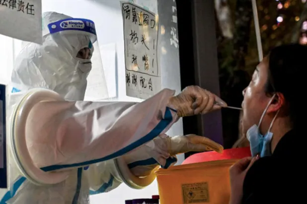 عامل صحي يجري فحص «بي سي آر» لصينية في شنغهاي أمس (أ.ف.ب)
