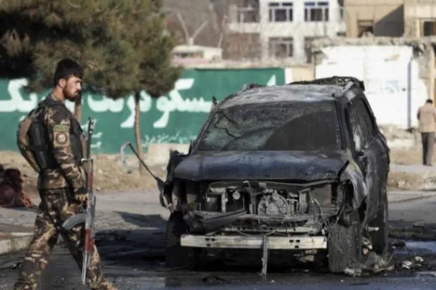 مسؤول أمني أفغاني يتفقد سيارة مدمرة بعد انفجار قنبلة في كابل (أرشيفية-أ.ب)
