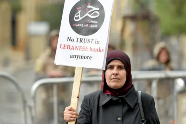 مودعة لبنانية ترفع يافطة في مظاهرة أمام مبنى البرلمان تؤكد عدم الثقة بالمصارف اللبنانية (إ.ب.أ)