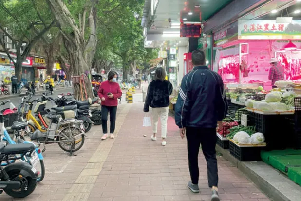 مشاة يمرون بجوار متاجر أعيد فتحها في غوانغزو الصينية بعد تشديدات واسعة النطاق (أ.ب)